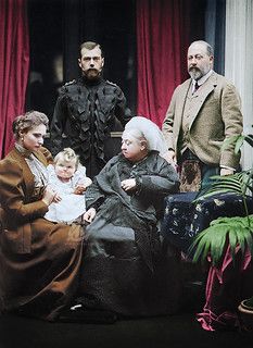 an old photo of three people and a baby in front of a red curtained room