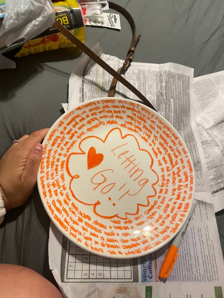 an orange and white bowl sitting on top of a table next to some paper towels