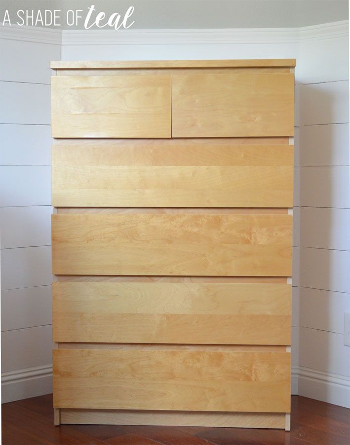 a wooden dresser sitting on top of a hard wood floor next to a white wall