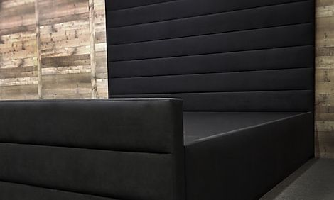 a black couch sitting in front of a brick wall