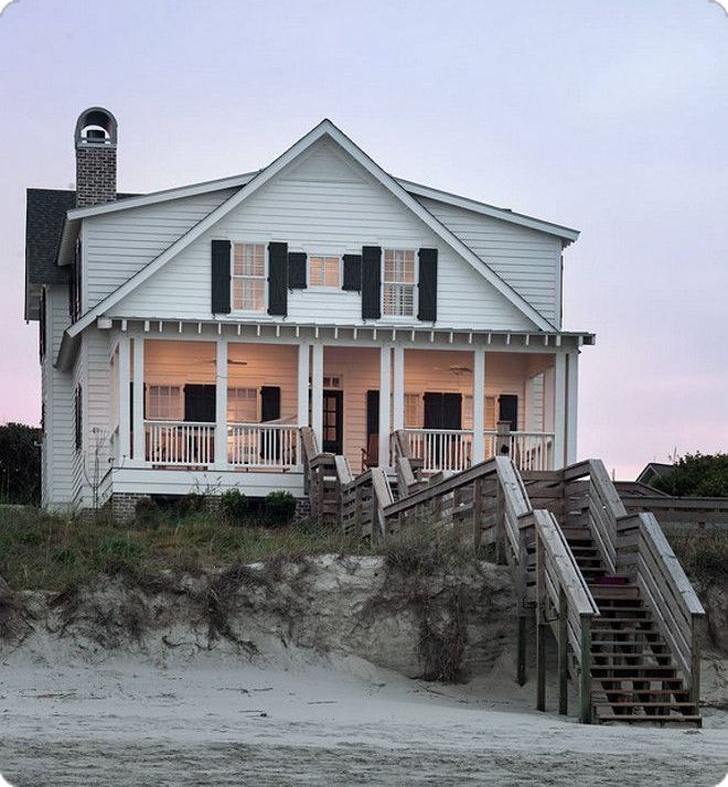 a white house on the beach with stairs leading up to it