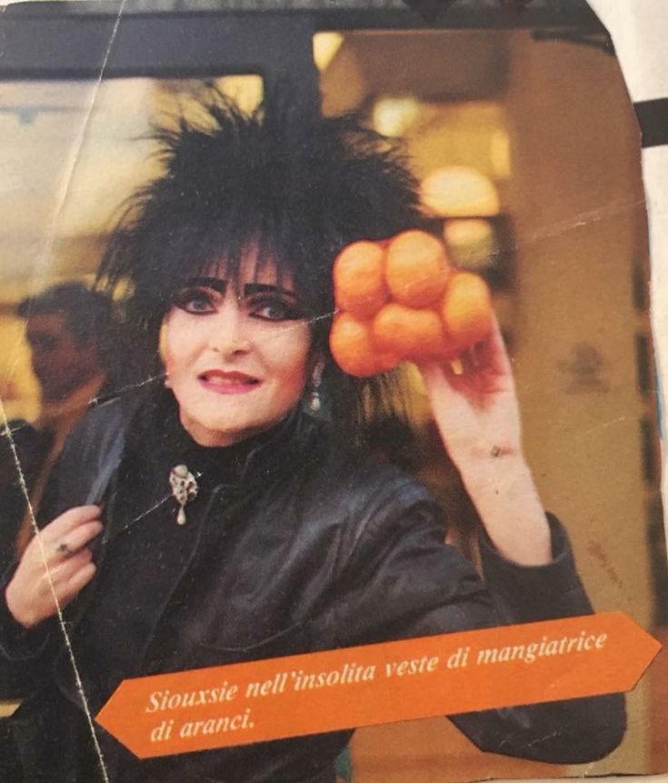 a woman with black hair holding oranges in front of her face and an advertisement on the side