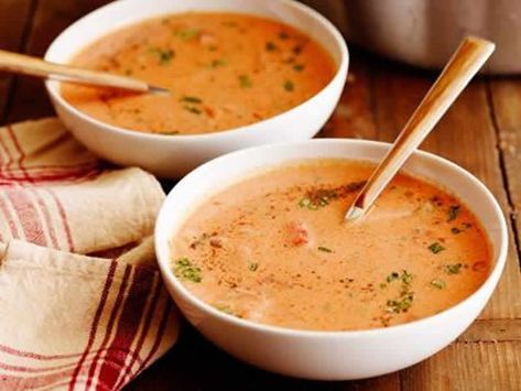 two bowls filled with soup on top of a wooden table