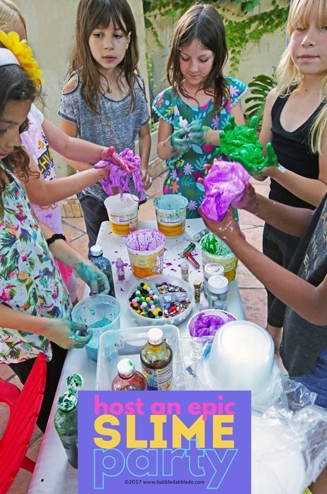 children are gathered around a table with slime party decorations