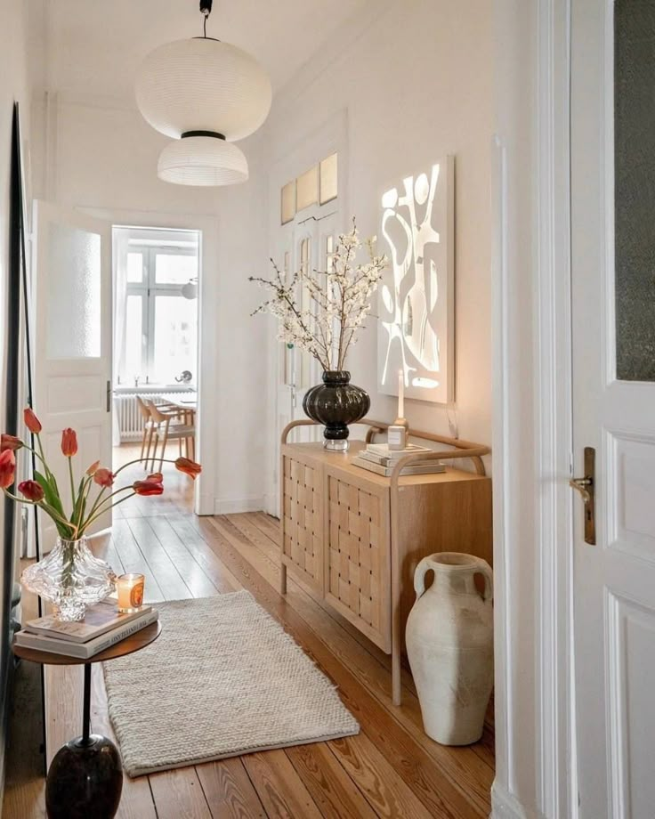 a living room filled with furniture and flowers on top of a wooden table next to a doorway