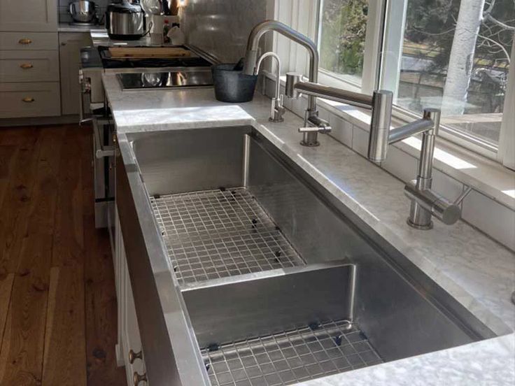 a stainless steel kitchen sink in front of a window