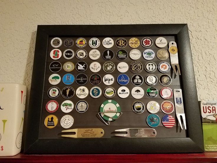 there is a framed display with many different badges on it and a cup next to it