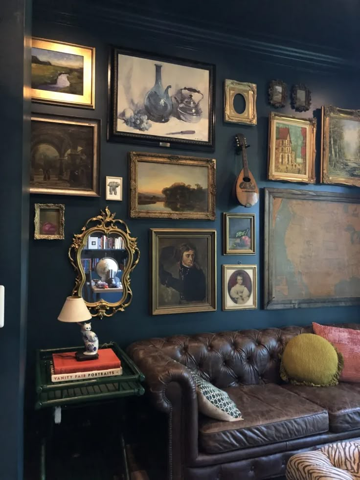 a living room filled with lots of framed pictures on the wall above a leather couch