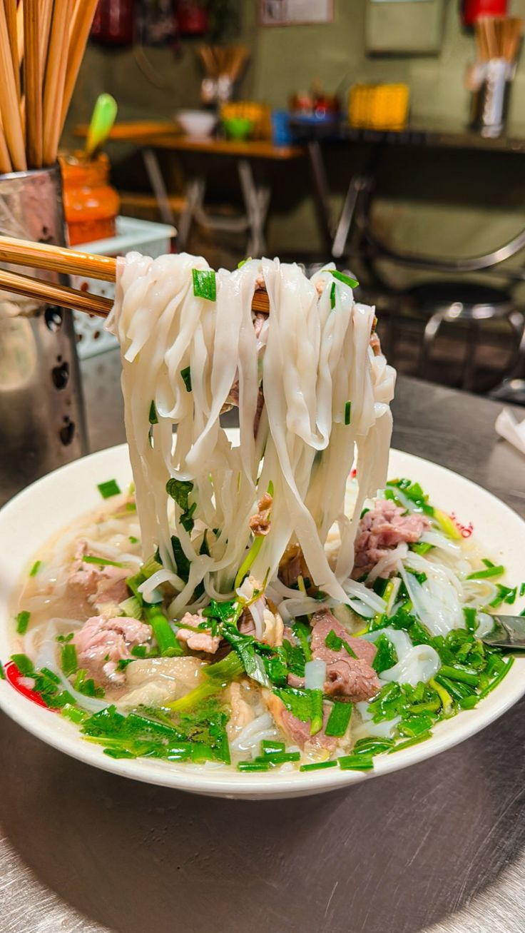 a white plate topped with lots of food and chopsticks sticking out of it