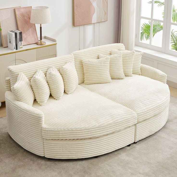 a large white couch sitting on top of a living room floor next to a window