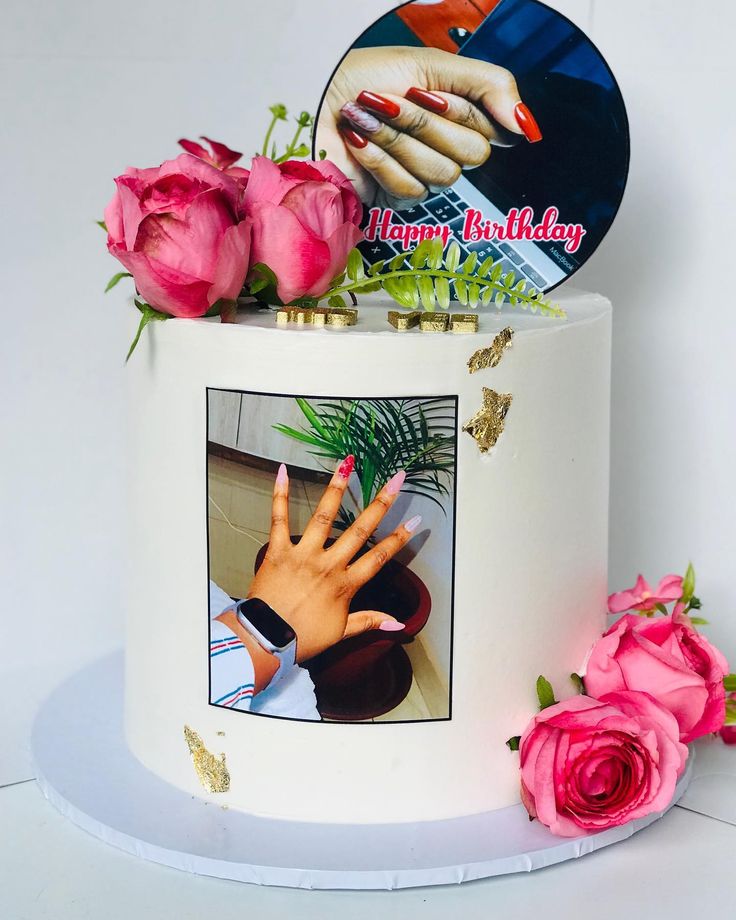 a white cake with pink flowers and a photo on it's side that says happy birthday