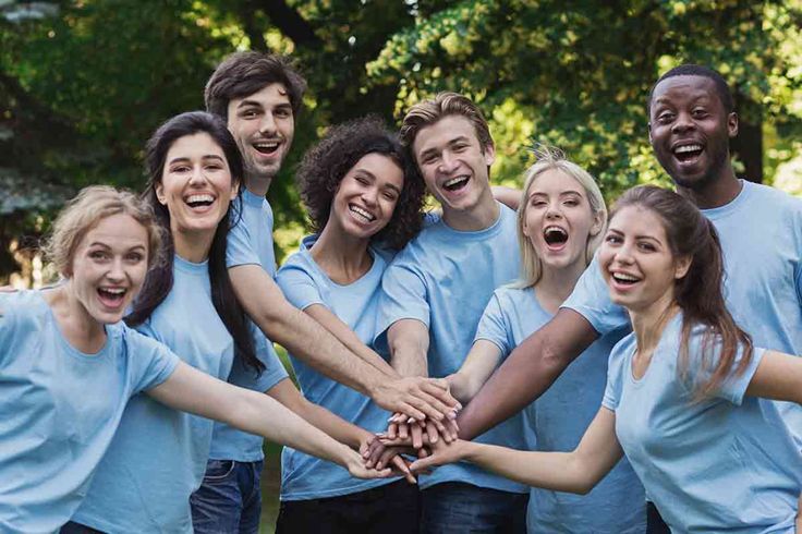 a group of people in blue shirts are holding hands together and smiling at the camera