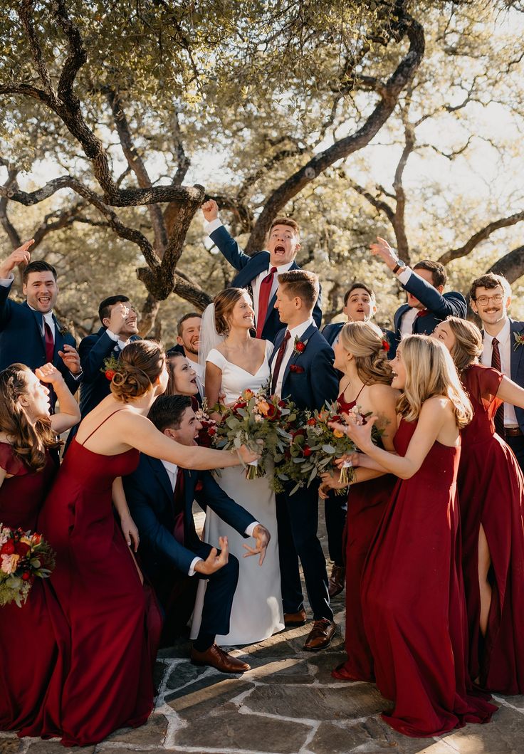 Fun excited wedding party surrounding bride and groom on wedding day wearing red bridesmaid dresses and groomsmen in blue suits Burgundy And Burnt Orange Wedding, Orange And Navy Blue Wedding, Trending Bridesmaid Dresses, Burnt Orange And Navy Blue, Bridesmaid Dresses Burgundy, Deep Red Wedding, Navy And Burgundy Wedding, Wedding Colors Red, Red Wedding Theme