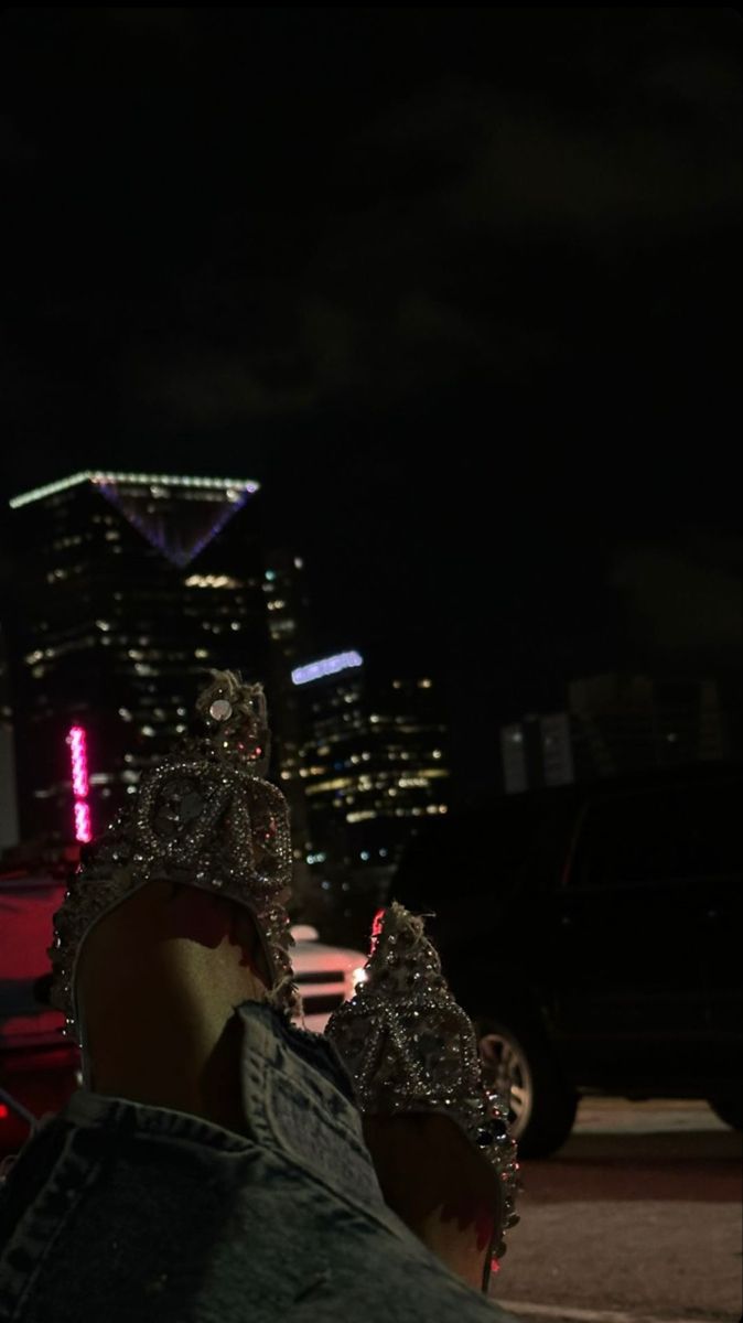 two people wearing crowns are standing in the street at night with city lights behind them