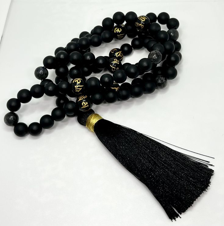 Step into the realm of spiritual enlightenment with our Black Obsidian and Labradorite Mala. Crafted with meticulously selected black obsidian and labradorite beads, each carrying its unique energy of protection and transformation. The black and gold obsidian beads, inscribed with the sacred mantra 'Om Mani Padme Hum,' resonate with divine wisdom and compassion, guiding your journey towards inner harmony. Completing this masterpiece is a sophisticated black and gold tassel, symbolizing the union Spiritual Obsidian Round Bead Jewelry, Spiritual Obsidian Jewelry With Round Beads, Black Spiritual Beaded Jewelry, Black Symbolic Jewelry With 8mm Beads, Spiritual Onyx Beads Jewelry 8mm, Symbolic Black Jewelry With 108 Beads, Spiritual Obsidian Jewelry For Meditation, Symbolic Black Jewelry For Healing, Spiritual Obsidian Beaded Jewelry