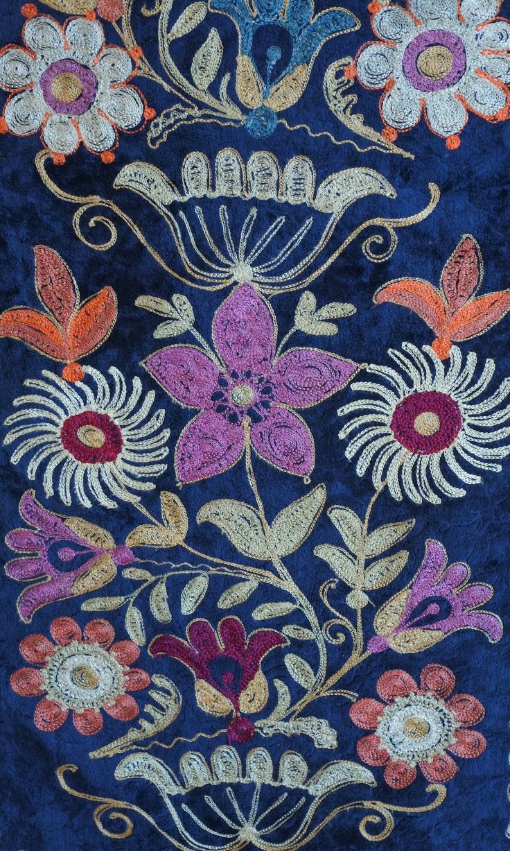 an embroidered cloth with colorful flowers and leaves on it's side, in the middle of