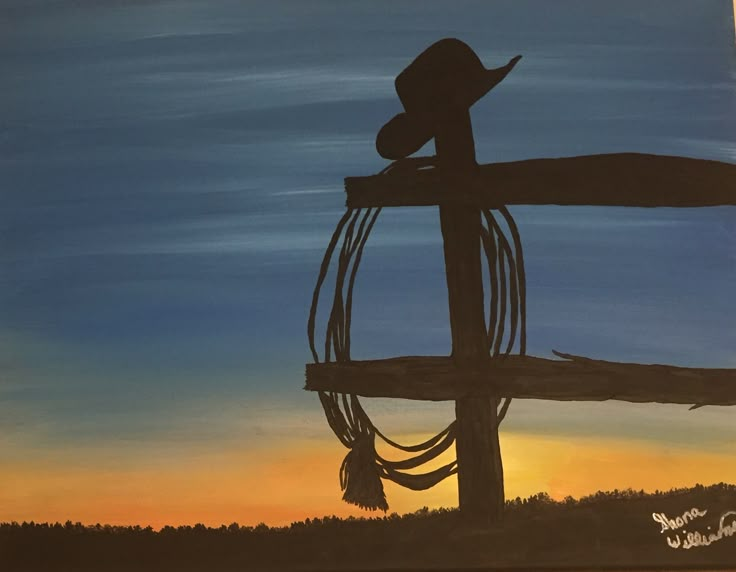 a painting of a cowboy hat and lasso on a wooden fence with the sun setting in the background