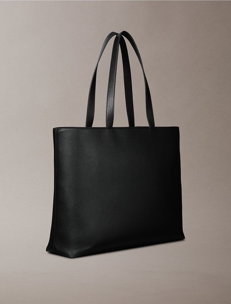 A modern classic, this tote bag features ample storage space for all the essentials. Crafted from durable faux leather with a fine pebbled texture. Finished with a tonal embossed monogram logo for iconic styling.  Material: 100% Polyurethane. All Black Outfits, Black Outfits, Black Tote, Monogram Logo, Black Tote Bag, Modern Classic, All Black, Storage Space, Calvin Klein