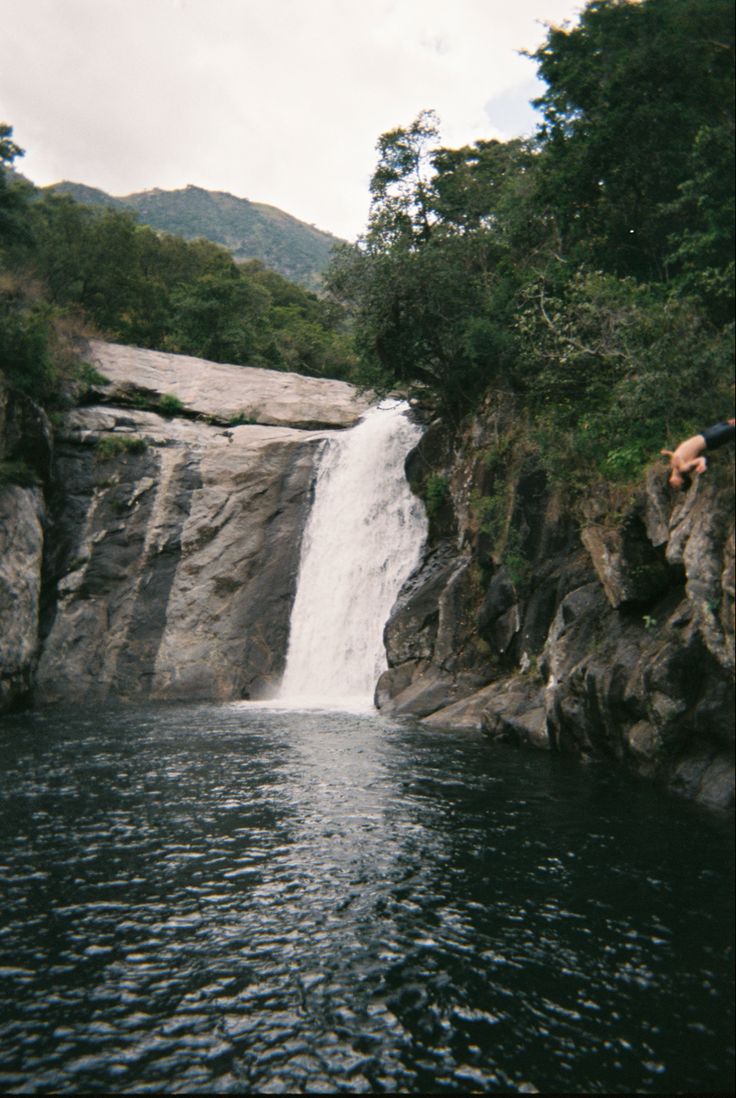 a man jumping off the side of a waterfall into a body of water