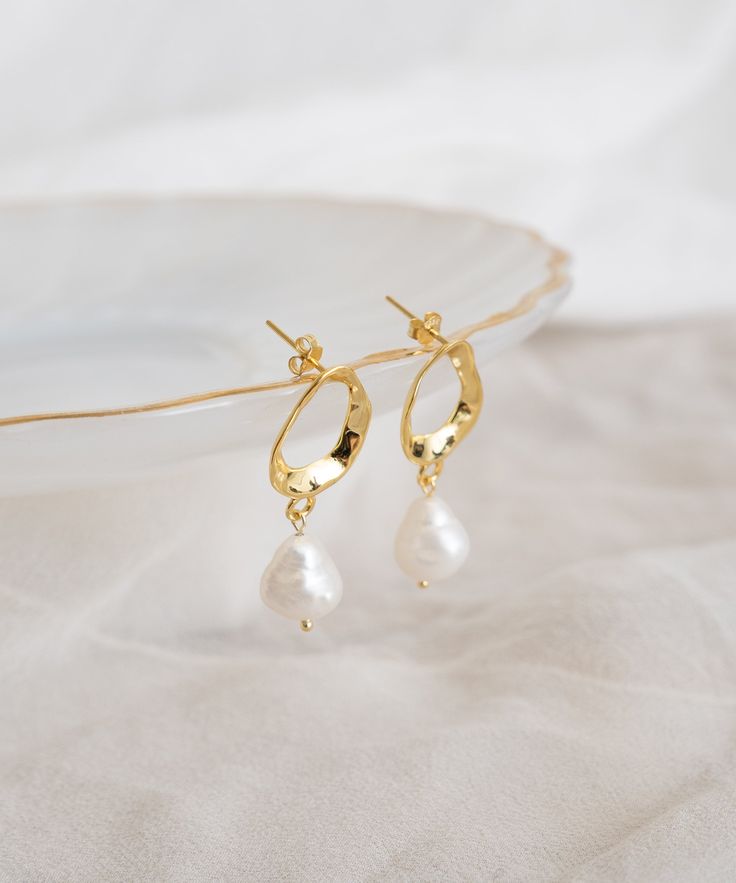 These Pearl Drop Earrings combine a hammered hoop with a baroque freshwater pearl for a look that's both nostalgic and modern at the same time. They're perfect when you need feminine energy but still want to keep your edge. The irregular shape makes them the perfect everyday statement. Pearl White 14k Gold-filled Drop Earrings, Elegant Pearl White 14k Gold-filled Pearl Earrings, 14k Gold-filled Pearl White Dangle Pearl Earrings, Elegant 14k Gold-filled Earrings With Pearl Charm, White Baroque Pearl Earrings, Round Shape, Pearl Drop Earrings Gold, Feminine Energy, Pearl Drop Earrings, Pearl Drop