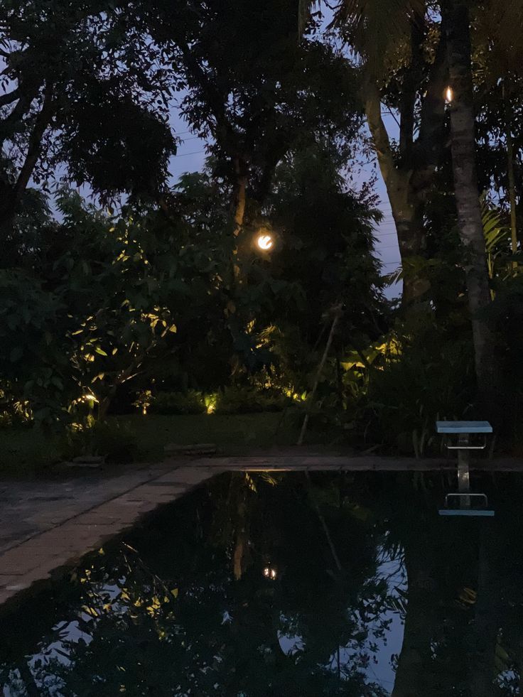 a bench sitting next to a swimming pool at night