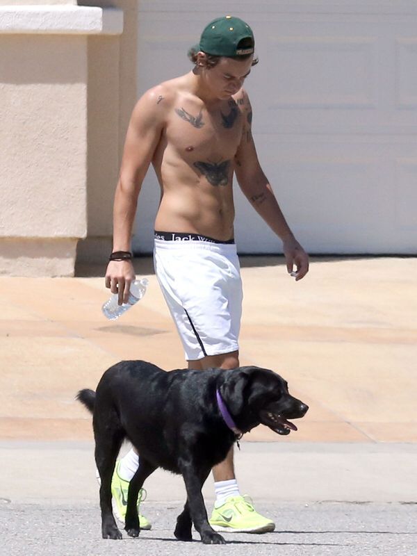 a shirtless man walking his dog in the street