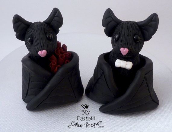 two black figurines with pink noses are sitting side by side on a white surface