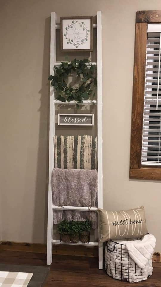 a white ladder is holding towels and other items in a room with wood flooring