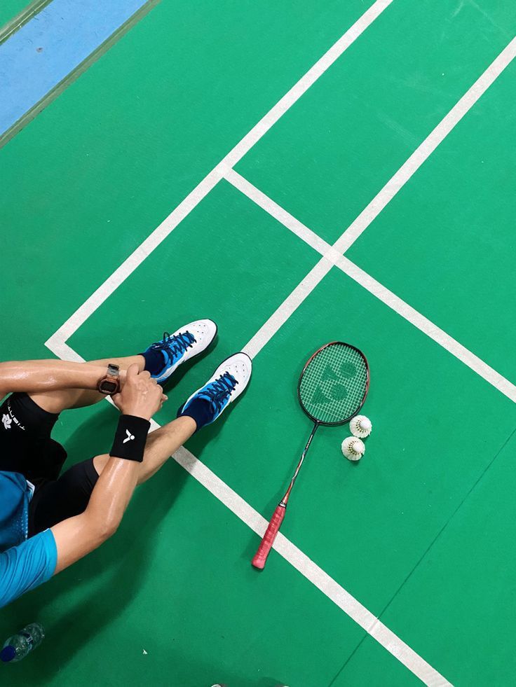 a man sitting on the ground with a tennis racket and ball in front of him