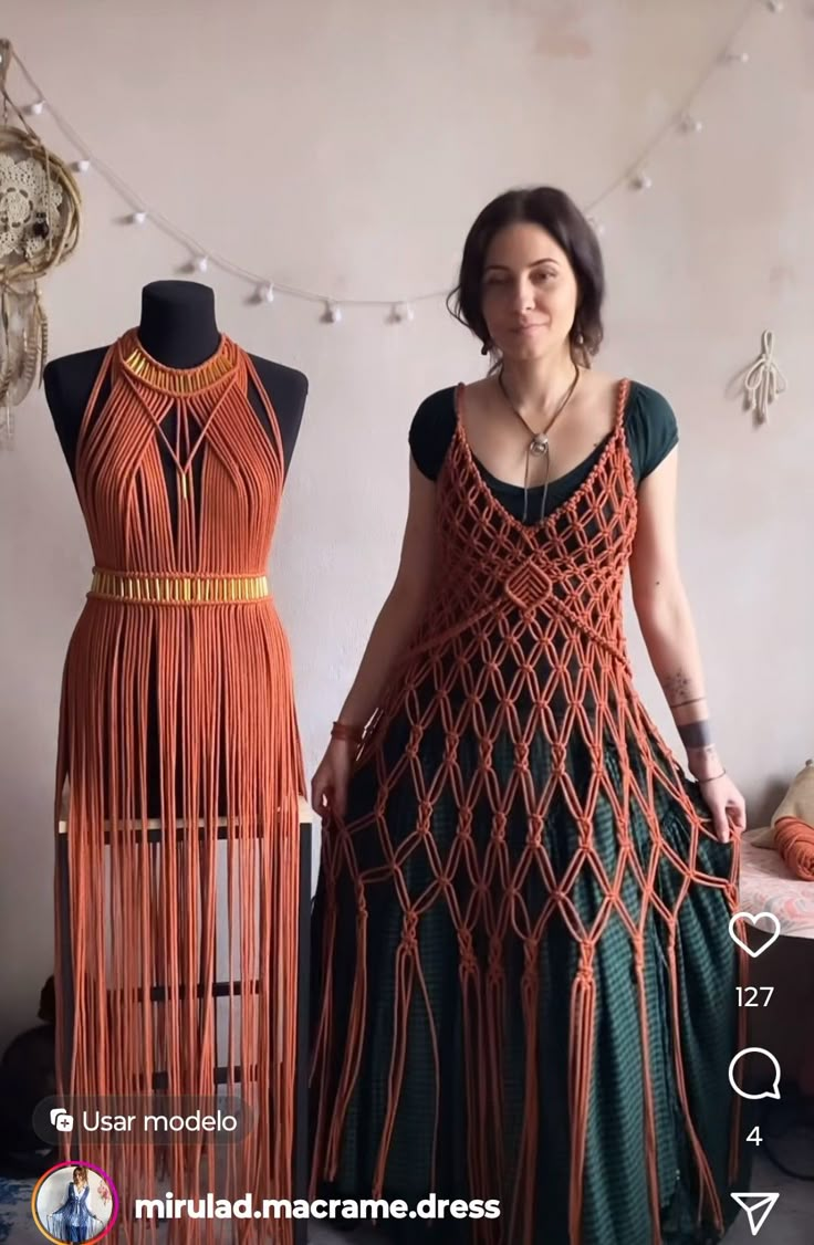 a woman standing next to two mannequins wearing dresses made out of yarn