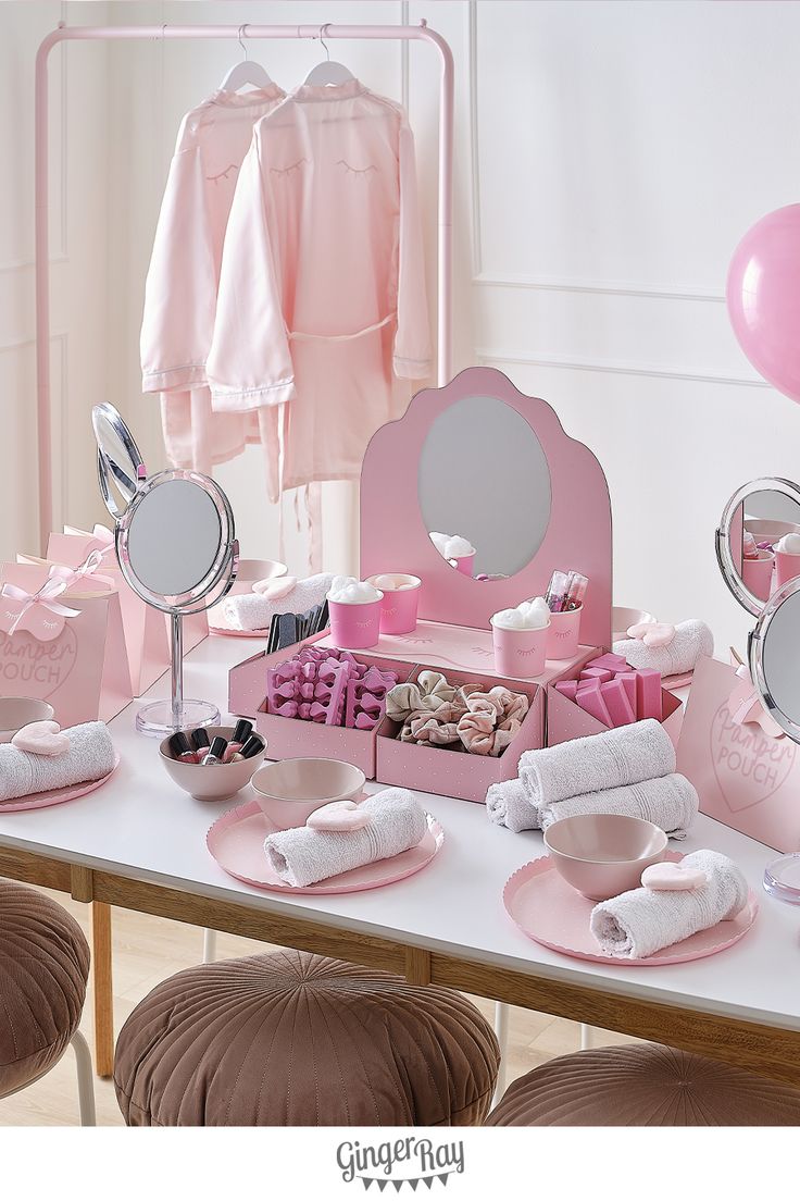 a table topped with lots of pink items next to mirrors and balloons in the background