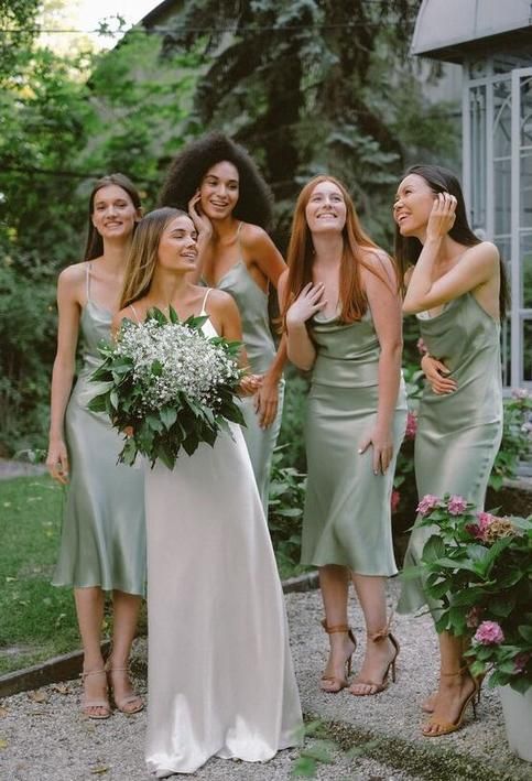 a group of women standing next to each other in front of a house with flowers