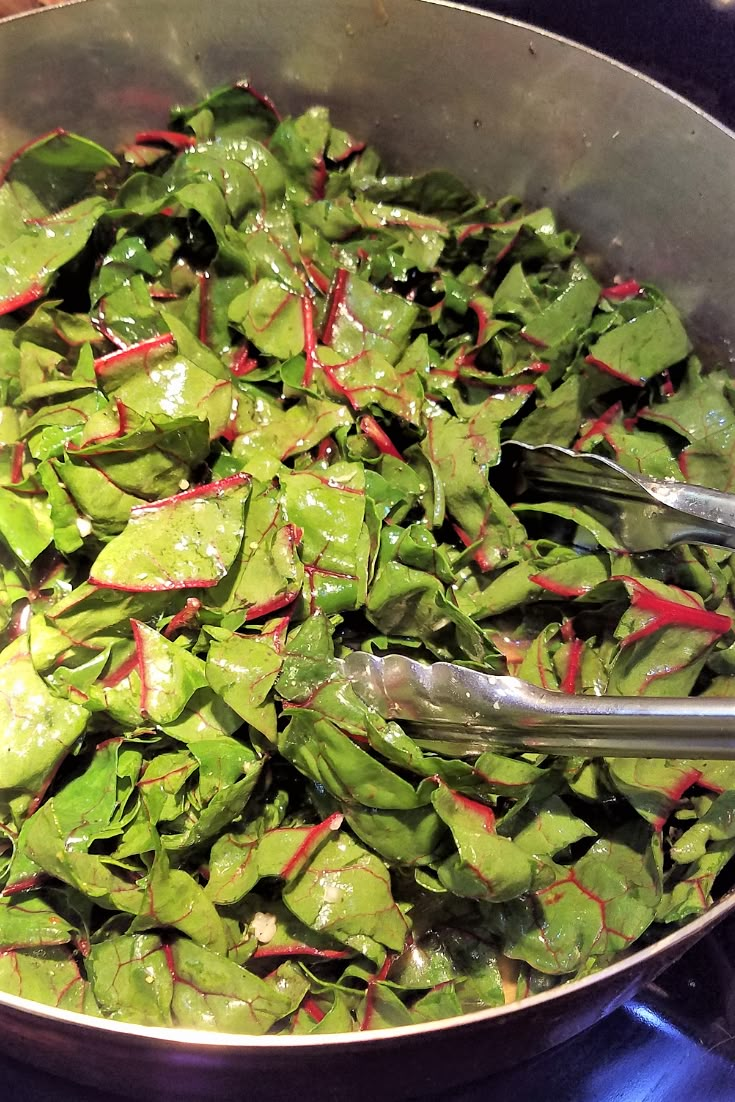 a pan filled with green vegetables on top of a stove