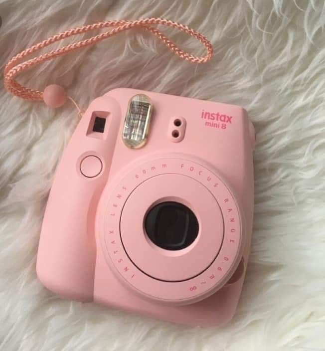 a pink camera sitting on top of a white blanket