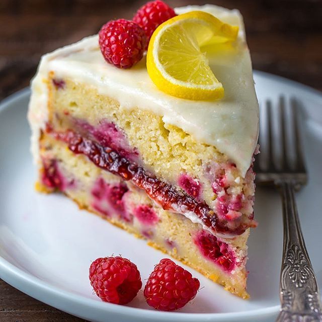 a piece of cake on a plate with raspberries