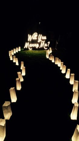 many paper lanterns are lit up in the dark, and there is a sign that says will you marry me?