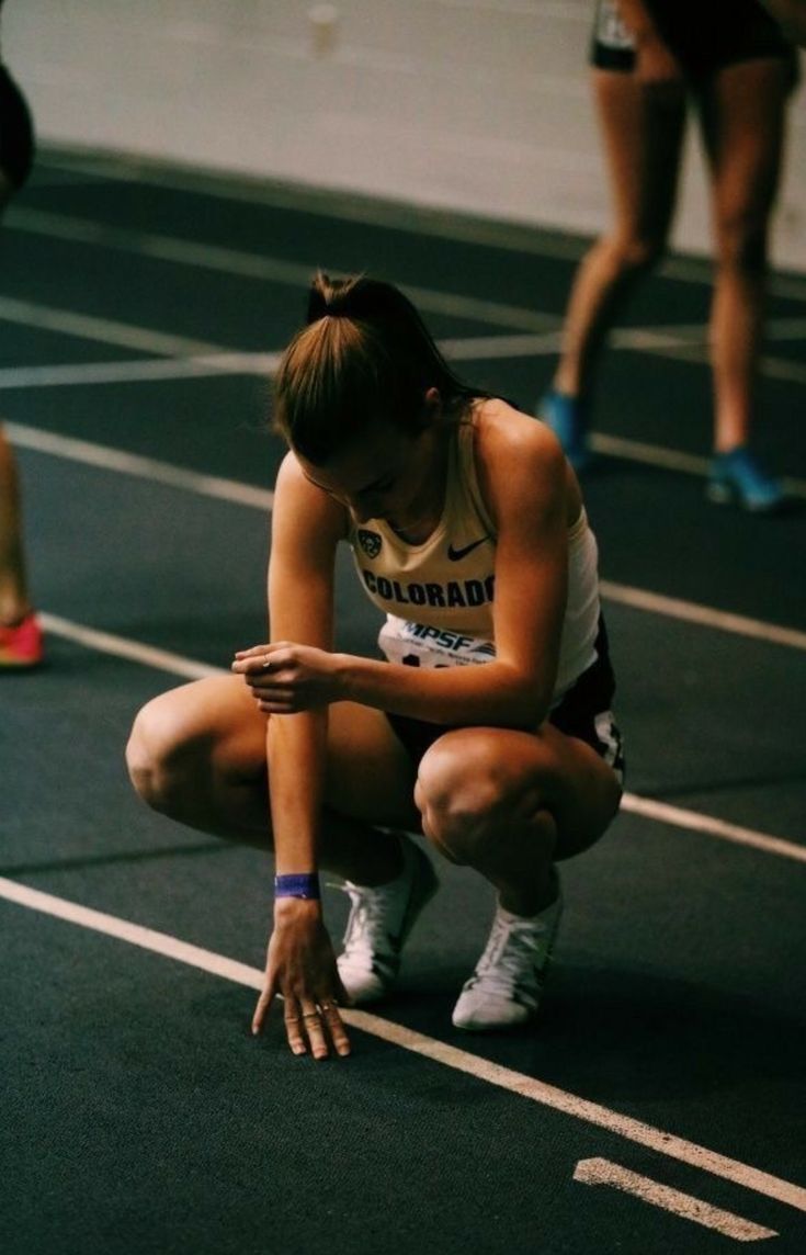 a woman kneeling down on top of a race track