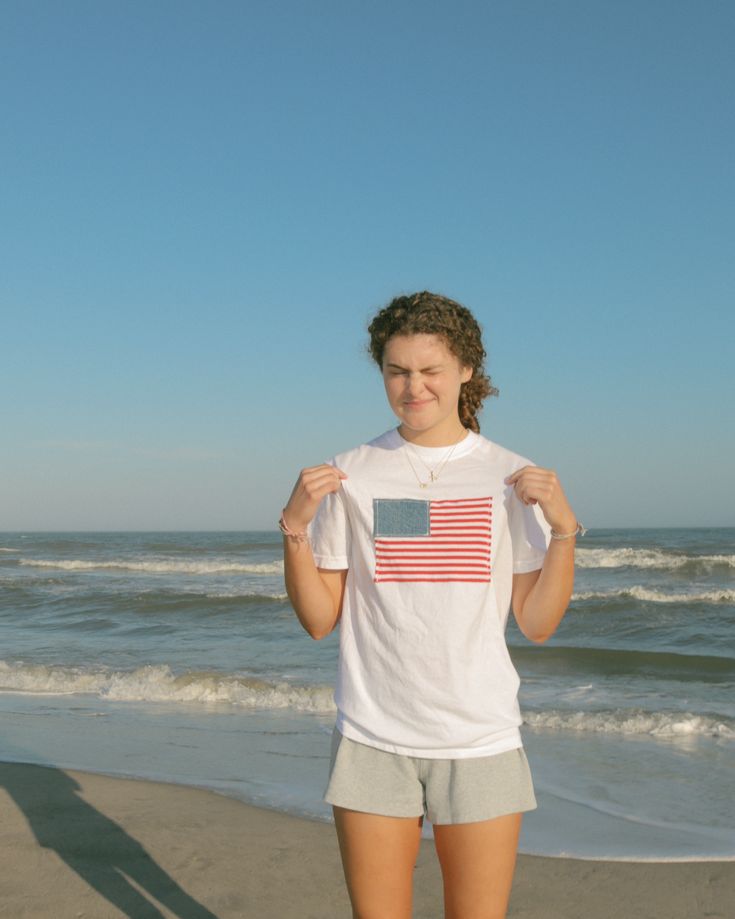 This tee takes the classic American flag shirt and takes it to a new level. Our American Flag tee is made with recycled fabrics to add a vintage and homemade feel. It is soft to the touch and fashionable - the perfect combo. Wear it to watch fireworks on the 4th of July, bike rides, or a summer party! Each t-shirt is designed and sewn by Ashley, Founder of Asho Designs. Each American Flag is made with recycled denim and striped fabric Tag me @ashodesigns when you wear your new shirt! I would love to see and repost Every order helps plant a tree! Check the "About" page for a total tree count! I am 5'5 and wearing a size Small. Watch Fireworks, Outer Banks Outfits, Beachy Outfit, Free People Aesthetic, America Outfit, Jean Short Outfits, American Flag Patch, Usa Girls, Unique Outfit