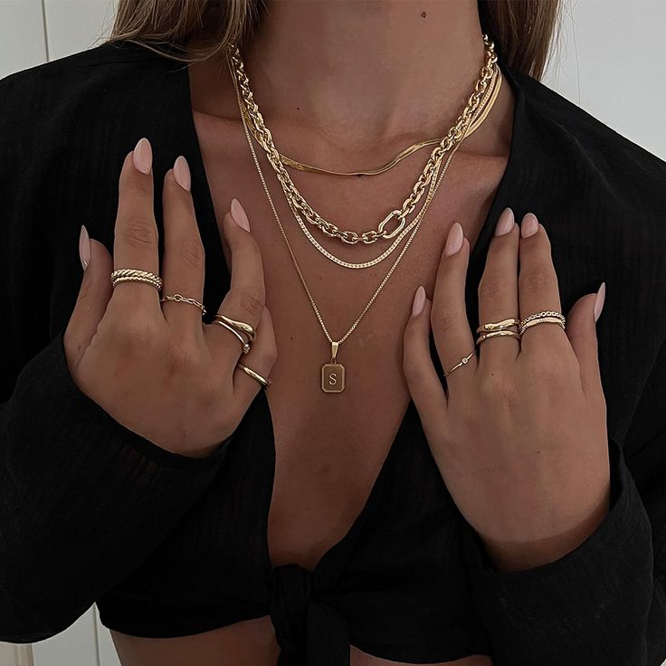 a woman in black shirt with gold jewelry on her chest and two rings around her neck