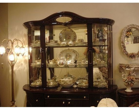 an antique china cabinet with glass doors and shelves filled with dishes, plates and other items