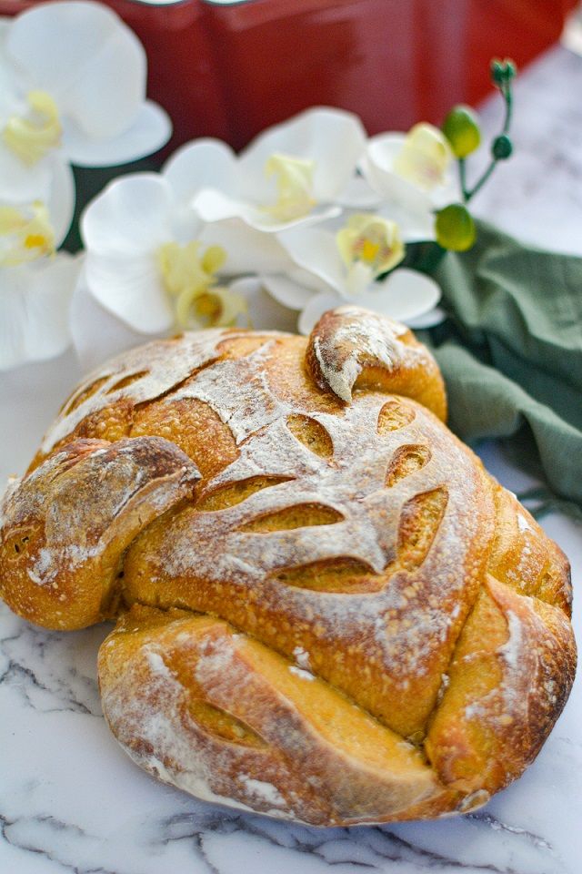 two loaves of bread sitting on top of a counter next to flowers and a potted plant