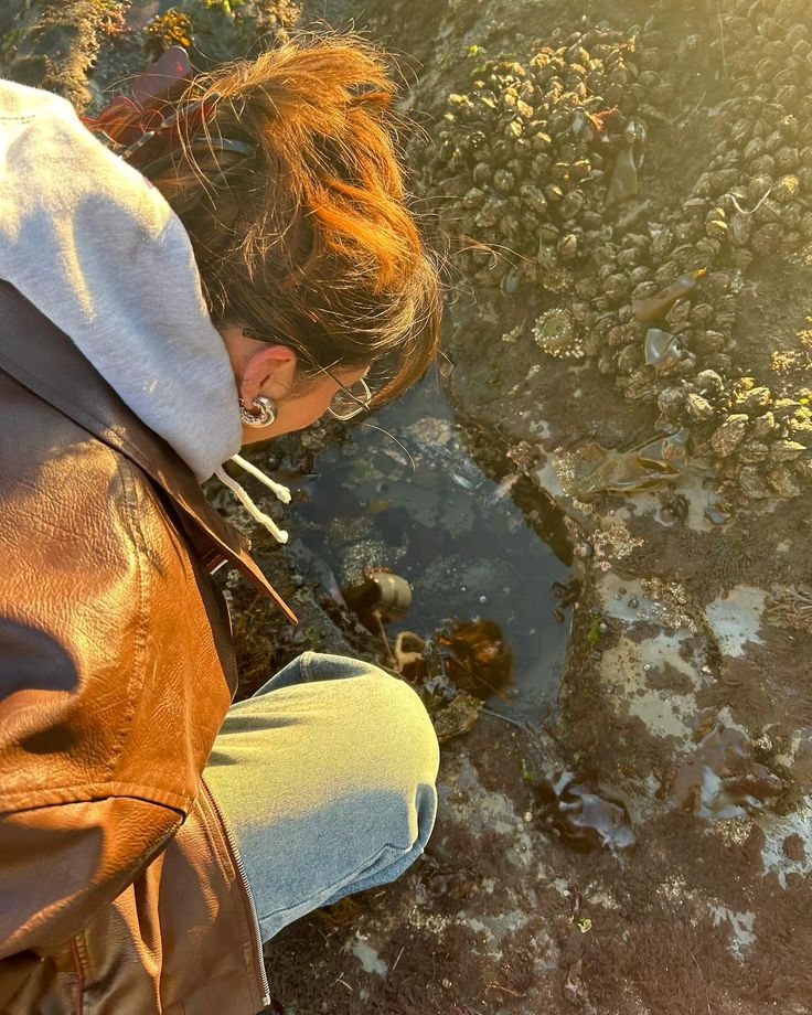 a woman sitting on the ground next to a puddle of water with her eyes closed