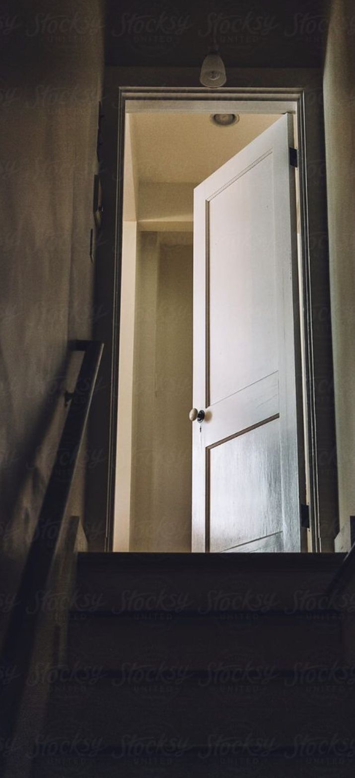 an open door leading to another room in a house with stairs and railings on either side