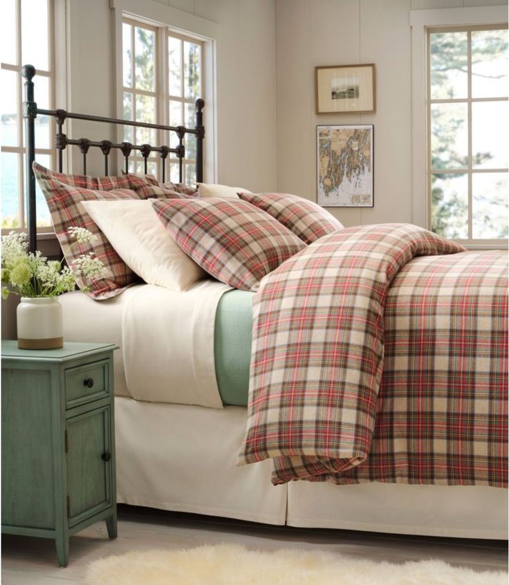 a bed with plaid comforter and pillows in a bedroom next to a nightstand table