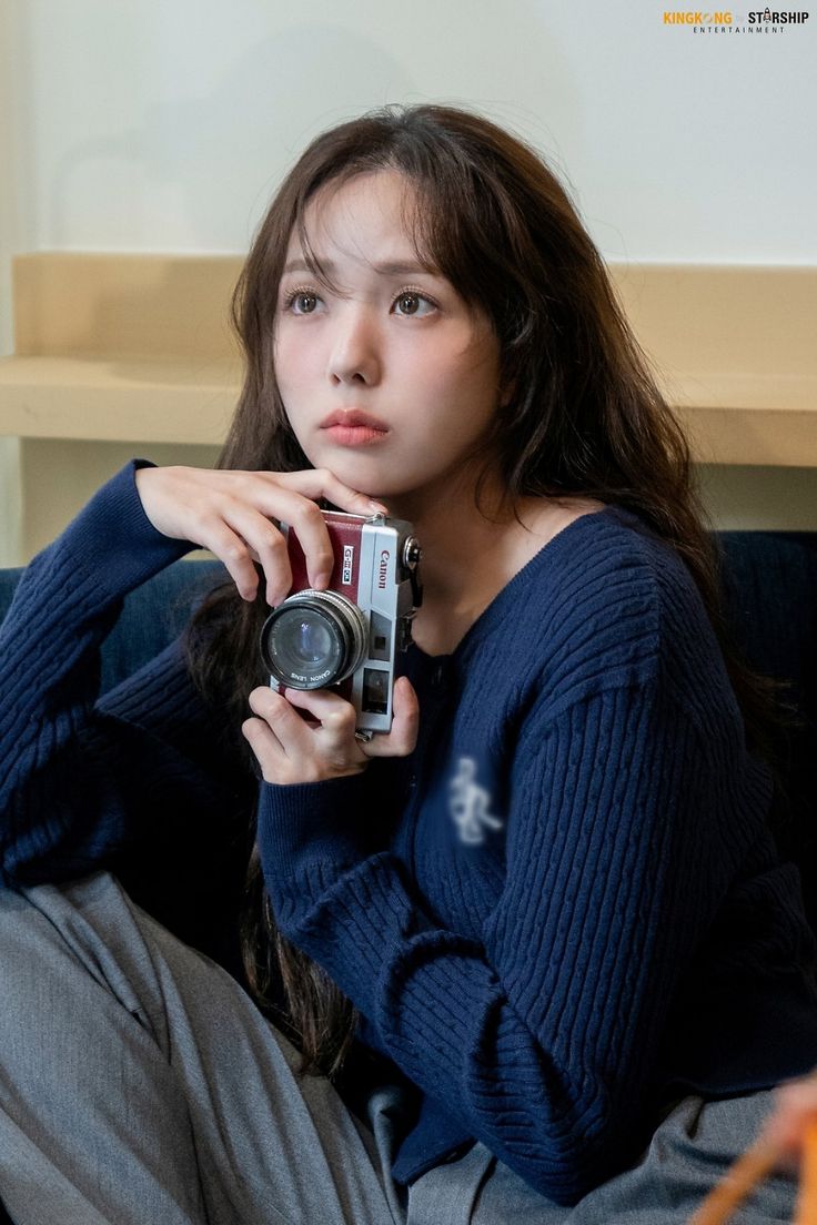 a woman sitting on a couch holding a camera