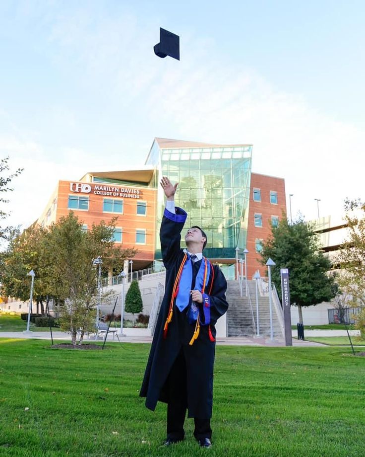 a man in graduation gown throwing a cap into the air