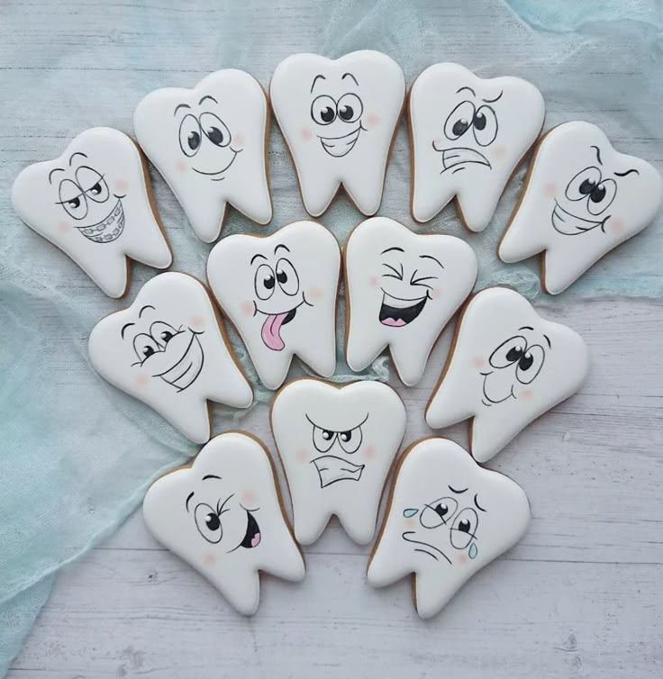 decorated cookies with cartoon faces are arranged in a circle on a white tablecloth background