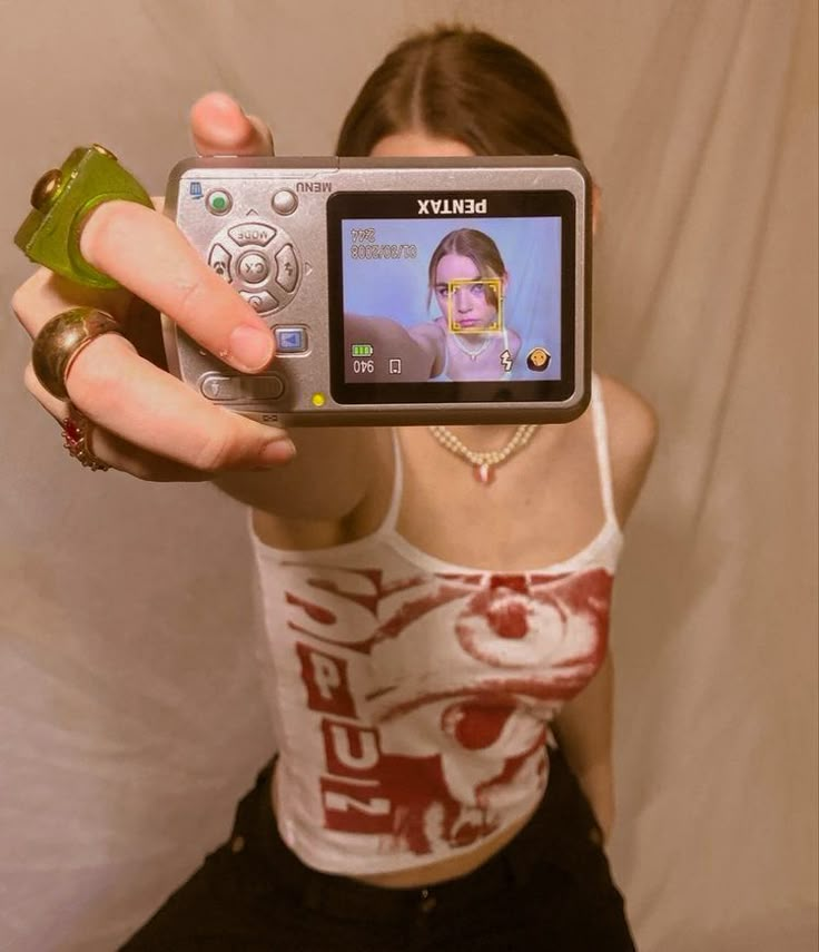 a woman holding up a camera to take a selfie in front of her face