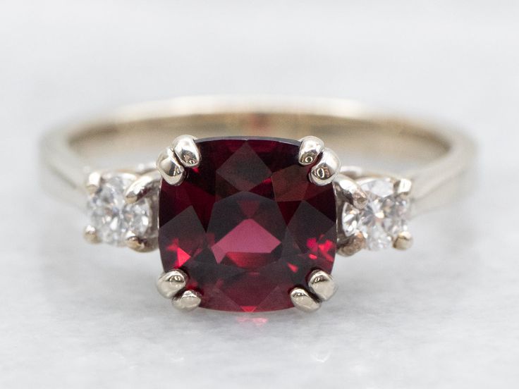 a red and white diamond ring with three diamonds around it