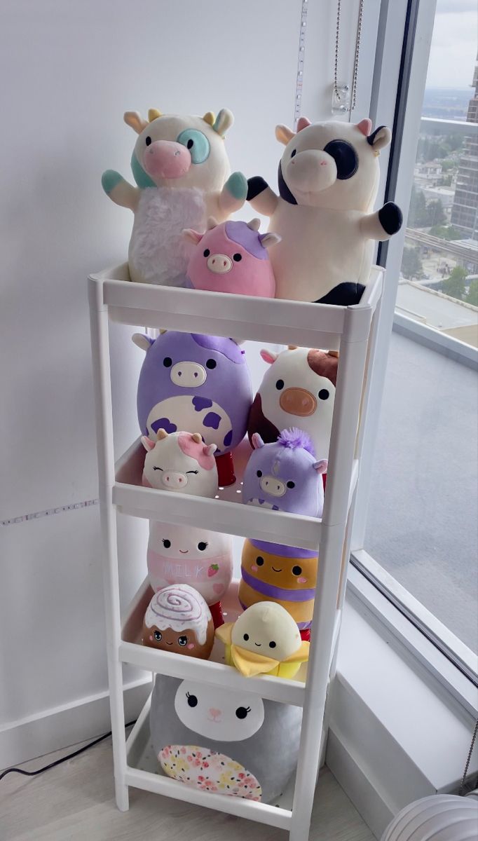 several stuffed animals sitting on top of a white shelf in front of a large window